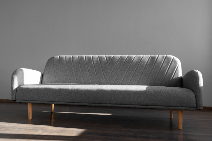 Sofa gris clair, moderne, avec accoudoirs et pieds en bois.