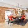 Une rénovation appartement ancien réalisée avec beaucoup de goût, dans cette grande pièce salle à manger, avec des murs en briques