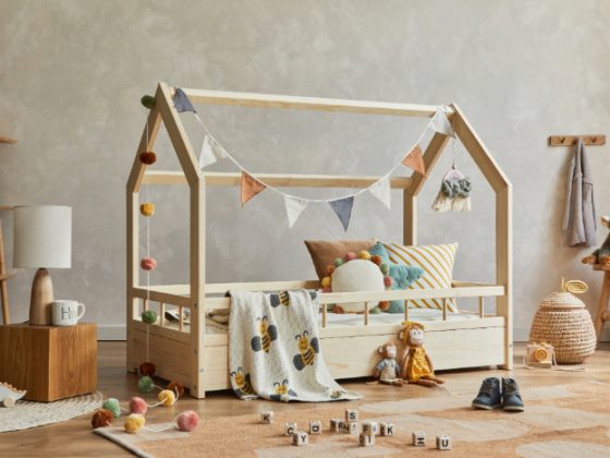 chambre de bébé style jungle avec lit, coussins, peluches, guirlande, jouets, tiroirs, tapis, étagère et paniers.