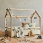 chambre de bébé style jungle avec lit, coussins, peluches, guirlande, jouets, tiroirs, tapis, étagère et paniers.