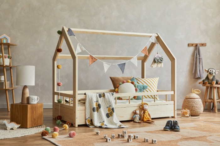 chambre de bébé style jungle avec lit, coussins, peluches, guirlande, jouets, tiroirs, tapis, étagère et paniers.