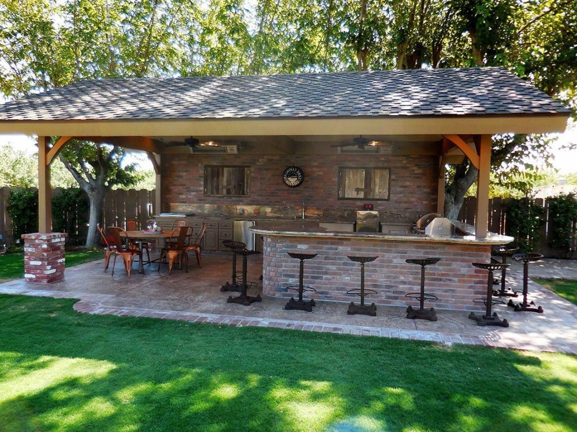 Cuisine extérieure en brique sous un abri en bois, avec bar, chaises hautes et coin repas