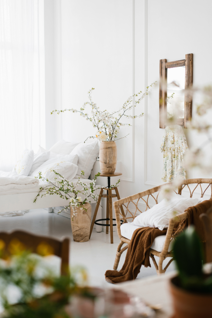 Intérieur lumineux au style naturel avec fleurs, objets en bois, plaid et chaise en osier.
