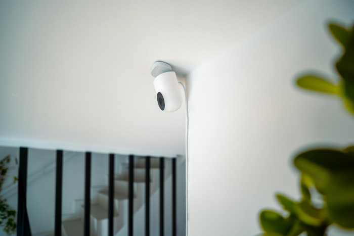 Caméra de surveillance blanche fixée au plafond dans un intérieur moderne.