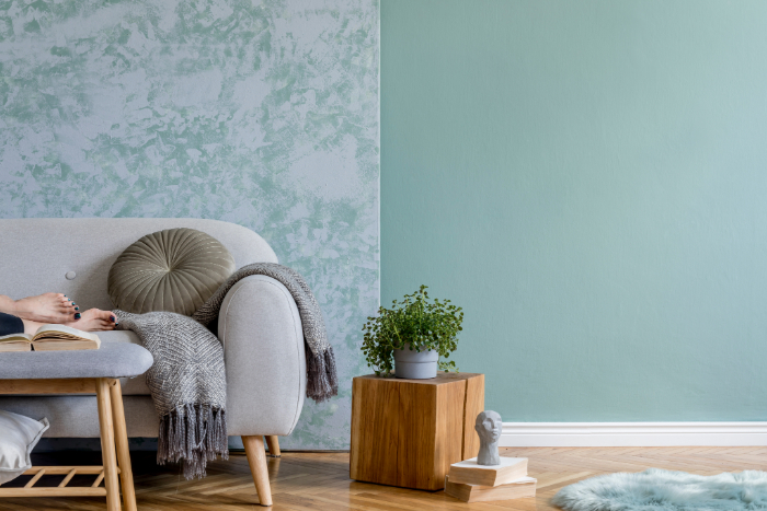 Salon avec canapé gris clair, plante et papier peint vert : ambiance calme pour se sentir bien chez soi.