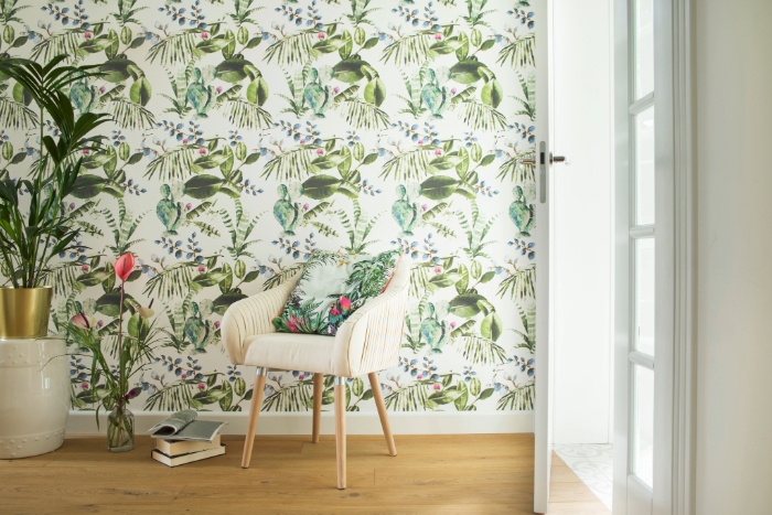 Déco bien-être d'un espace incluant fauteuil beige avec coussin floral, plantes vertes et papier peint botanique lumineux.