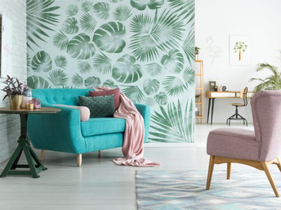 Déco bien-être d'un salon moderne avec mur à motifs feuilles tropicales, plantes, canapé turquoise, fauteuil rose, table ronde et tapis.