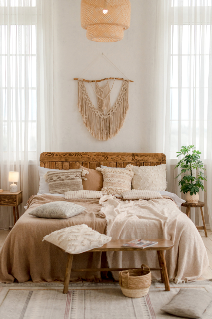 Chambre lumineuse avec meubles en bois naturel, plantes, macramé mural et lumière douce.