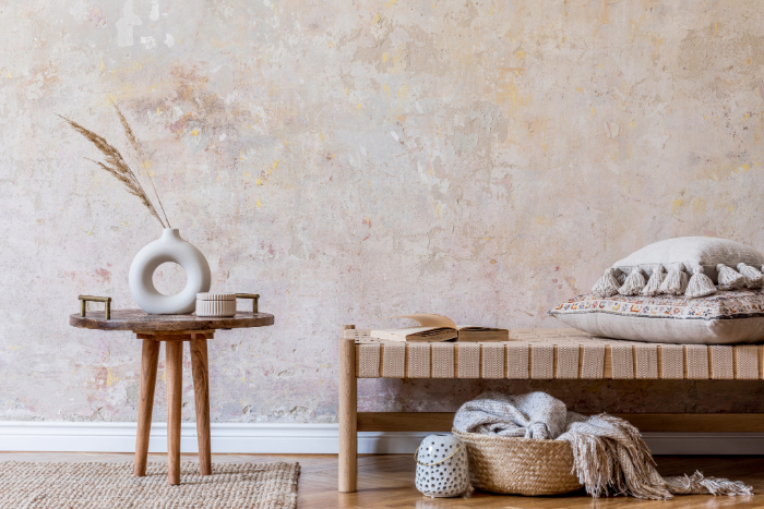 Déco minimaliste d'un intérieur avec des tons neutres, vase blanc, coussins et panier tissé.