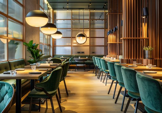 Décoration restaurant avec matériaux en bois et velours, éclairage doux et design épuré.
