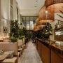 Décoration restaurant avec lumière tamisée, bois naturel, suspensions en osier, plantes vertes et bougies.