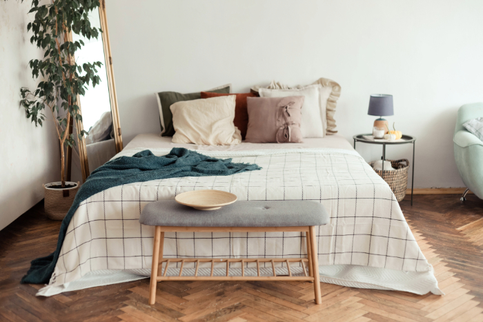 Chambre inclut linge doux, coussins colorés, plante verte, tapis, fauteuil avec décor naturel.