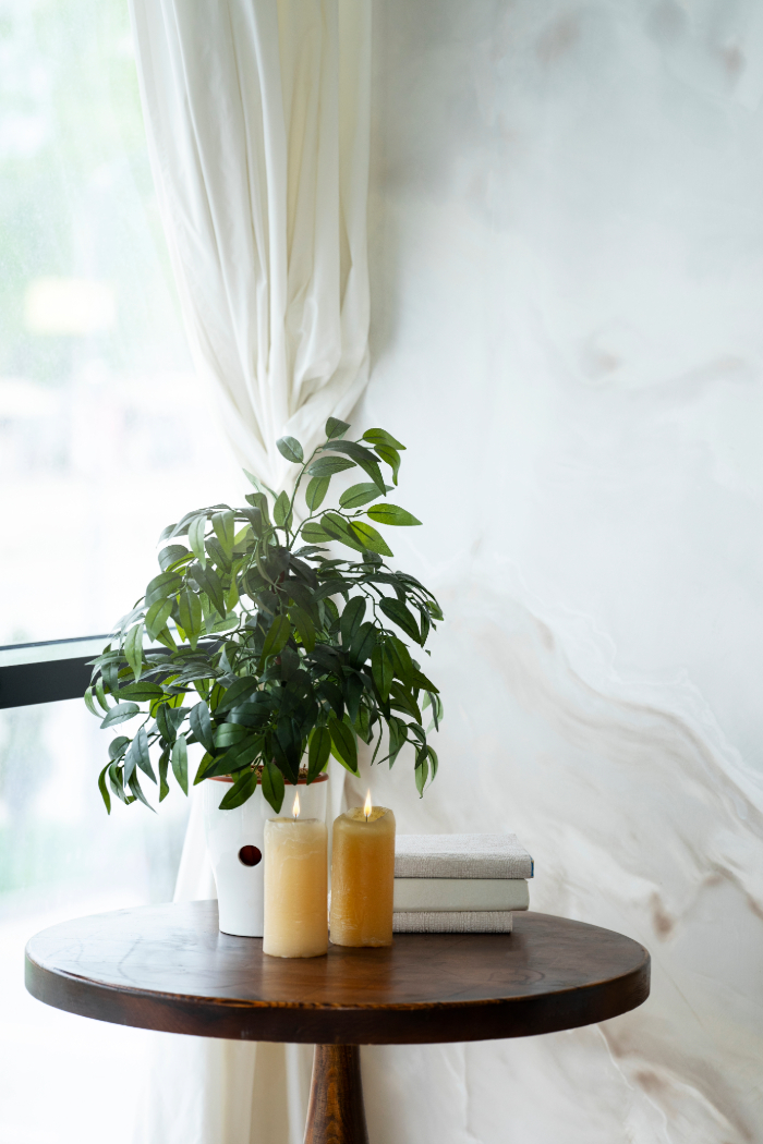 Espace lumineux et épuré, incluant plantes, bougies, et livres sur une table en bois.
