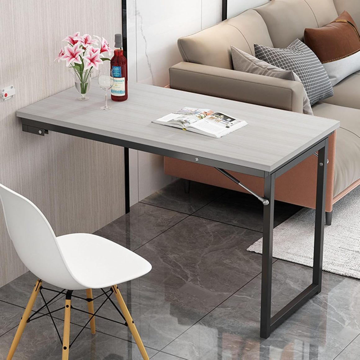 un petit espace aménagé avec table à manger murale rabattable, chaise blanche design et canapé beige.