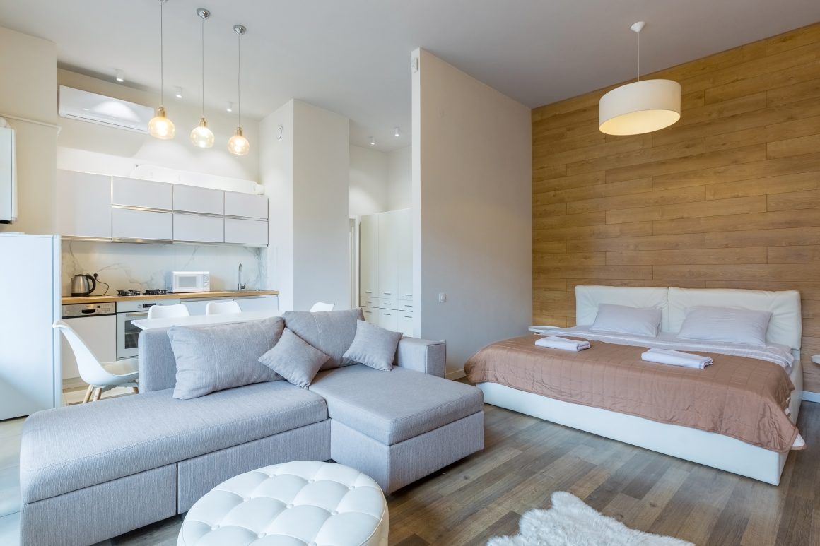 Aménagement d'un studio avec une cuisine ouverte sur salon et un coin nuit avec lit séparé avec un seul mur.