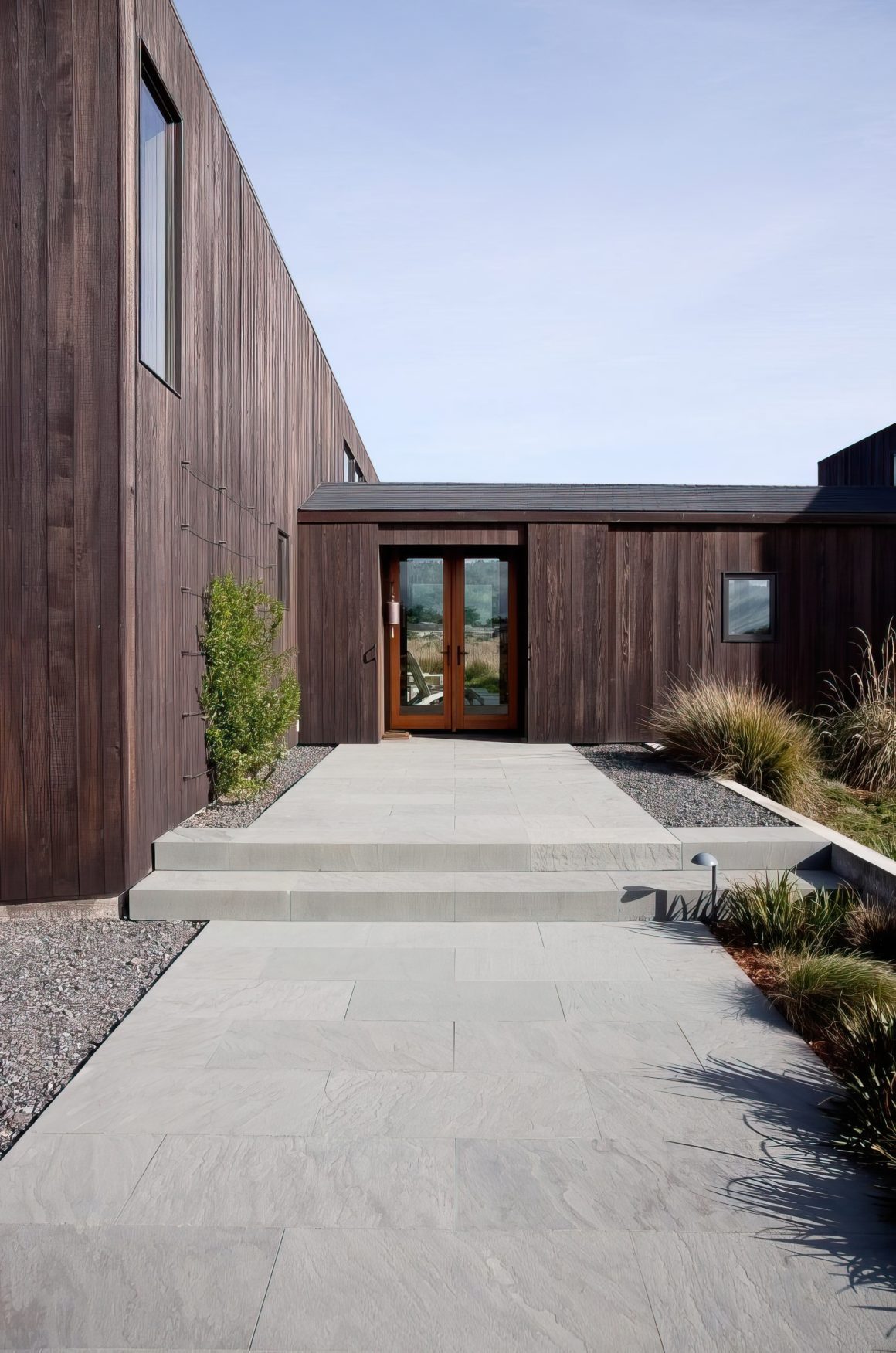 Extérieur maison aménagé avec des dalles en béton et décoré avec des plantes.