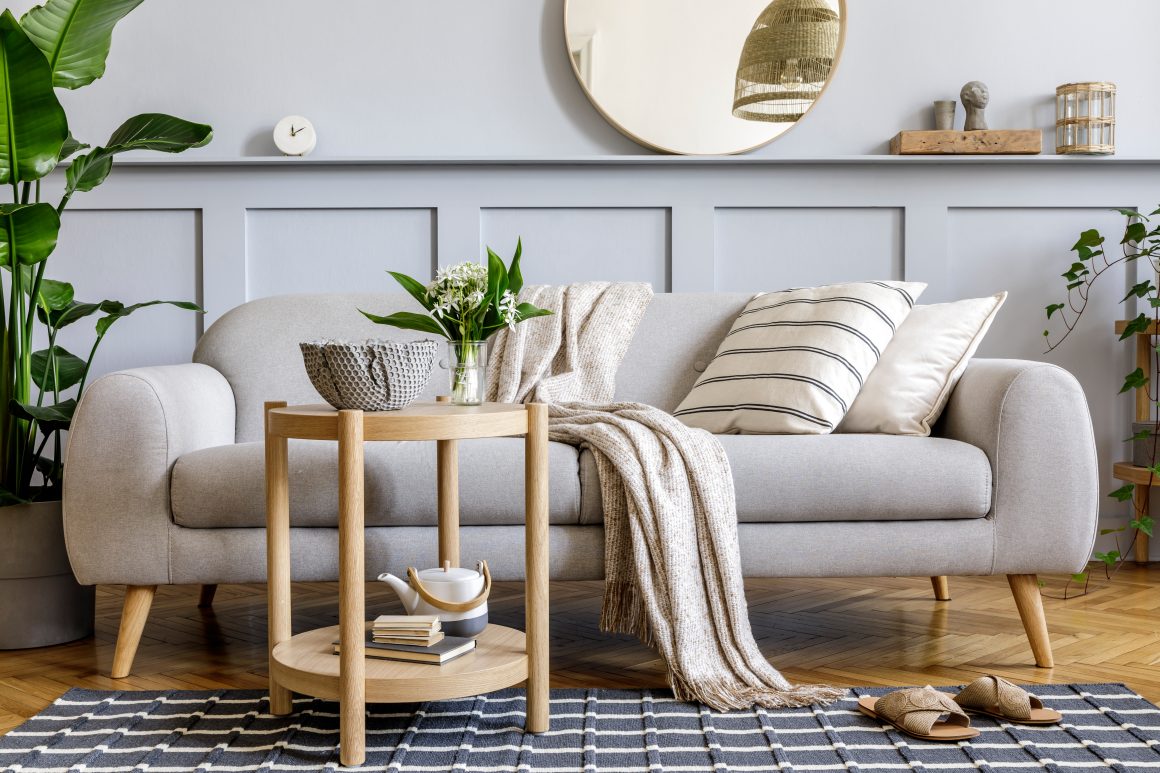 Déco salon incluant une table basse en bois avec vase fleurs, bougies, plantes et miroir.