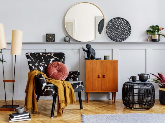 Coin salon avec fauteuil fleuri, miroir rond, lampadaires, plantes et objets de déco tendance 2025.