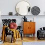 Coin salon avec fauteuil fleuri, miroir rond, lampadaires, plantes et objets de déco tendance 2025.