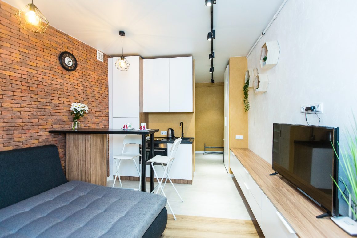 Studio aménagé avec canapé convertible, table à manger et une petite cuisine ouverte.