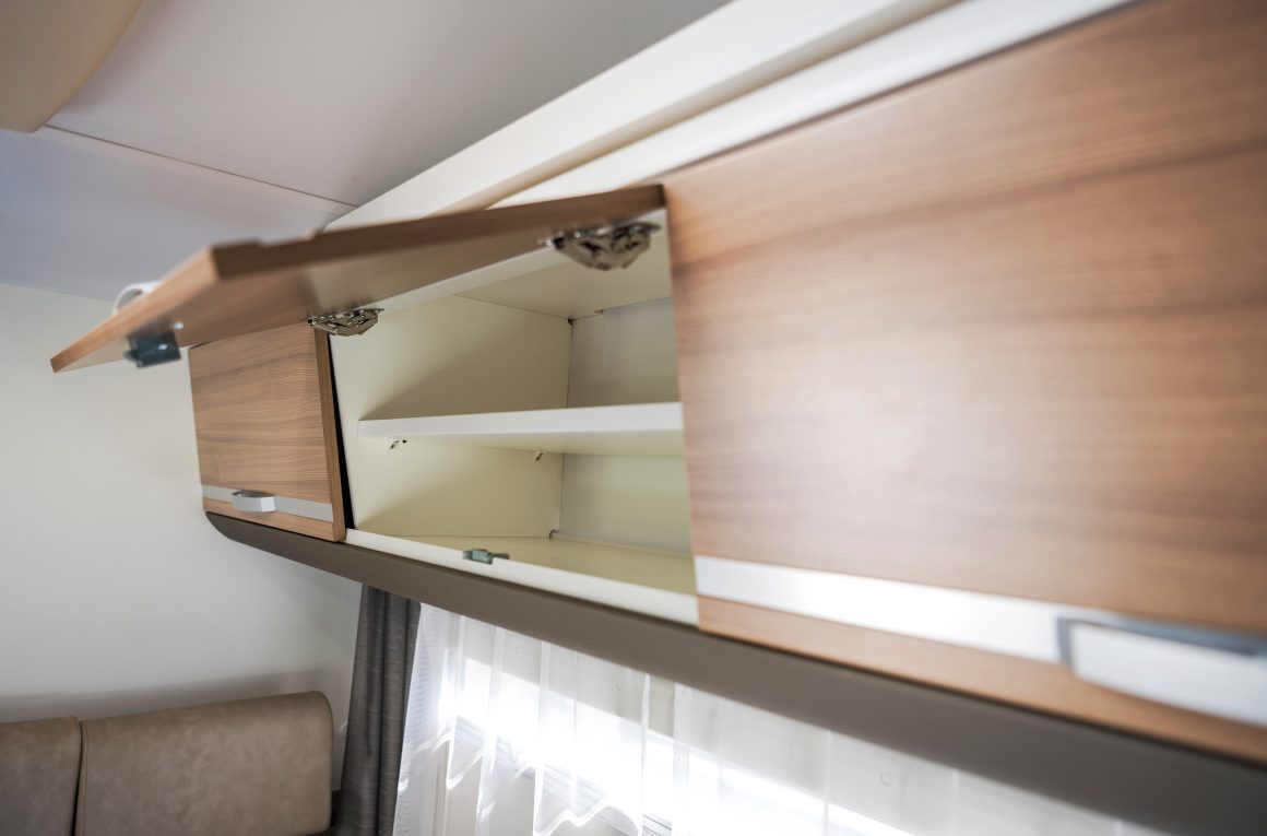 Placard vide suspendu en bois clair au-dessus d'une fenêtre avec rideaux.