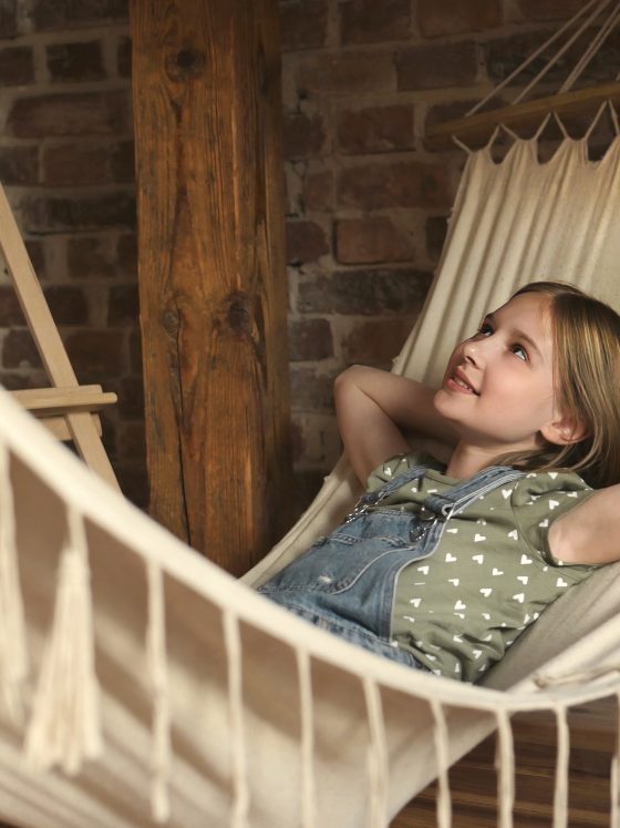 Fille détendue dans un hamac intérieur beige.