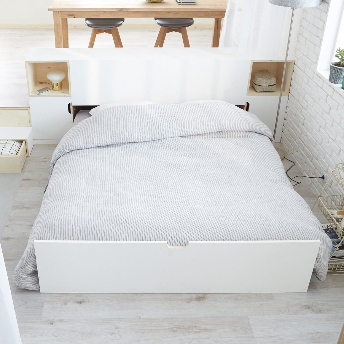 Aménagement d'un petit appartement 30m2 avec un lit caché sous une estrade dans le salon.