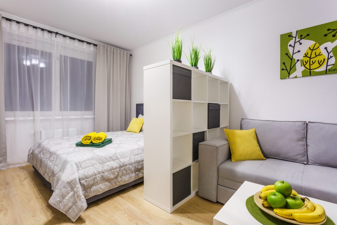 Chambre et salon séparés par un meuble étagère blanc avec boîtes noires