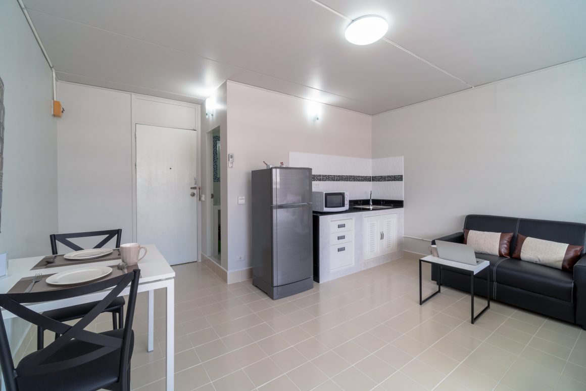 Aménagement studio incluant cuisine équipée, salon et salle à manger avec mobilier minimaliste.
