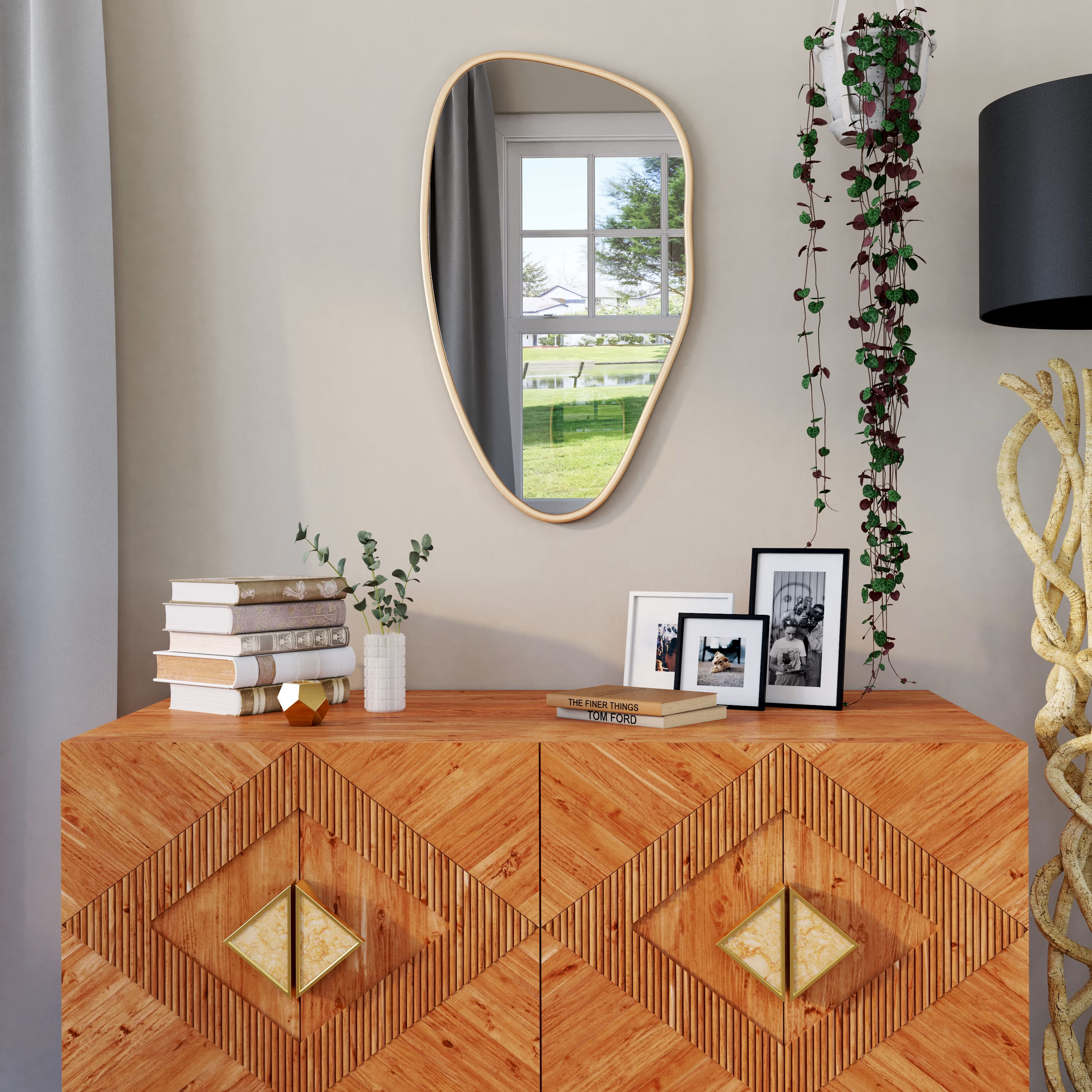 Déco petit appartement avec miroir, plante suspendue et une commode en bois sculpté avec livres et cadres photo.