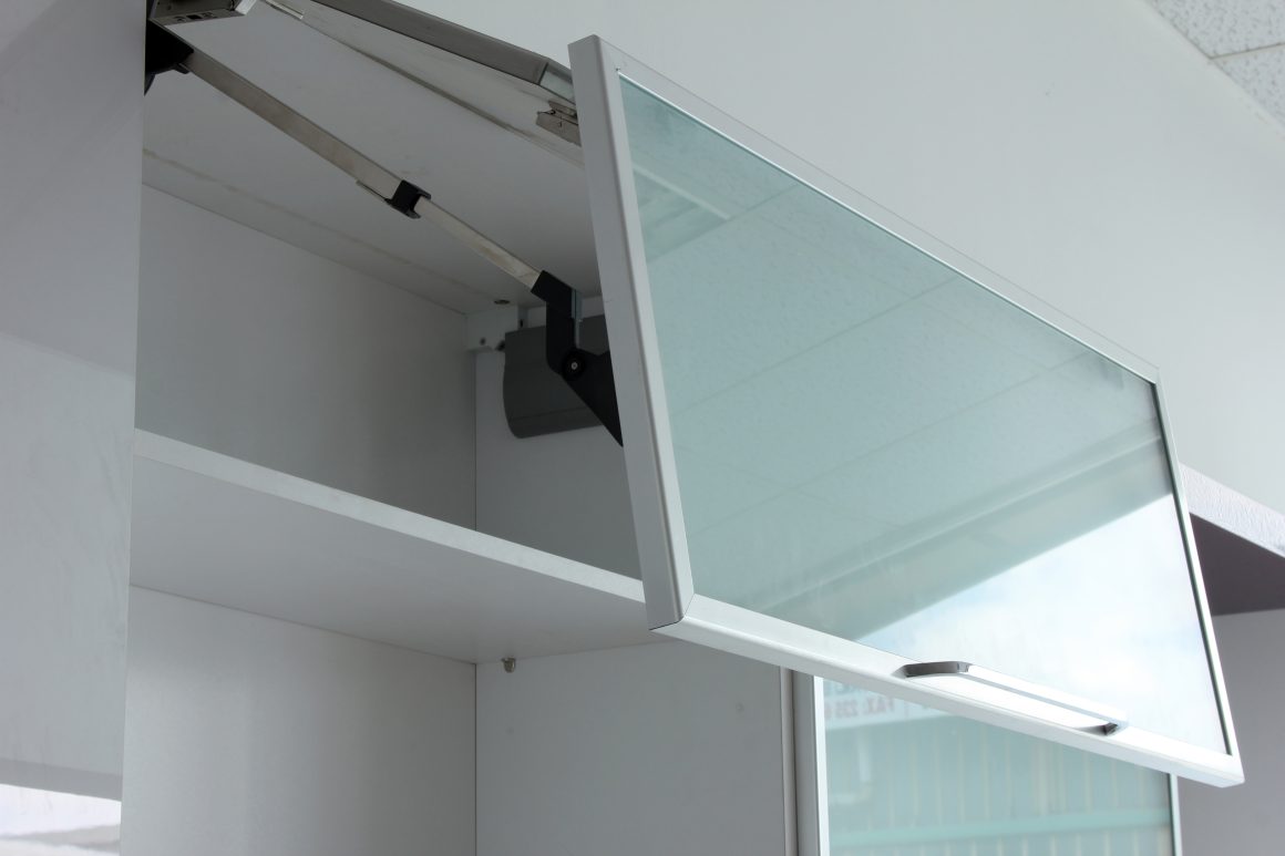 Armoire murale blanche avec porte à charnières en verre ouverte.