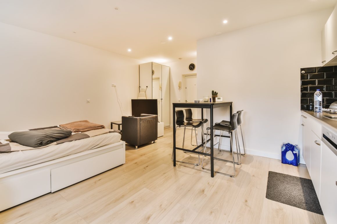 Aménager un studio 20m2 avec canapé-lit, table haute, chaises, fauteuil et cuisine équipée.