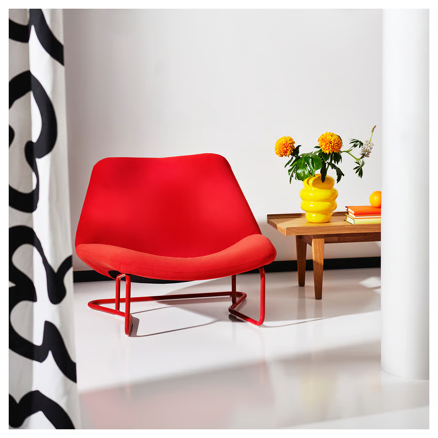 Chaise rouge moderne, table en bois, avec vase jaune, dans un intérieur épuré.