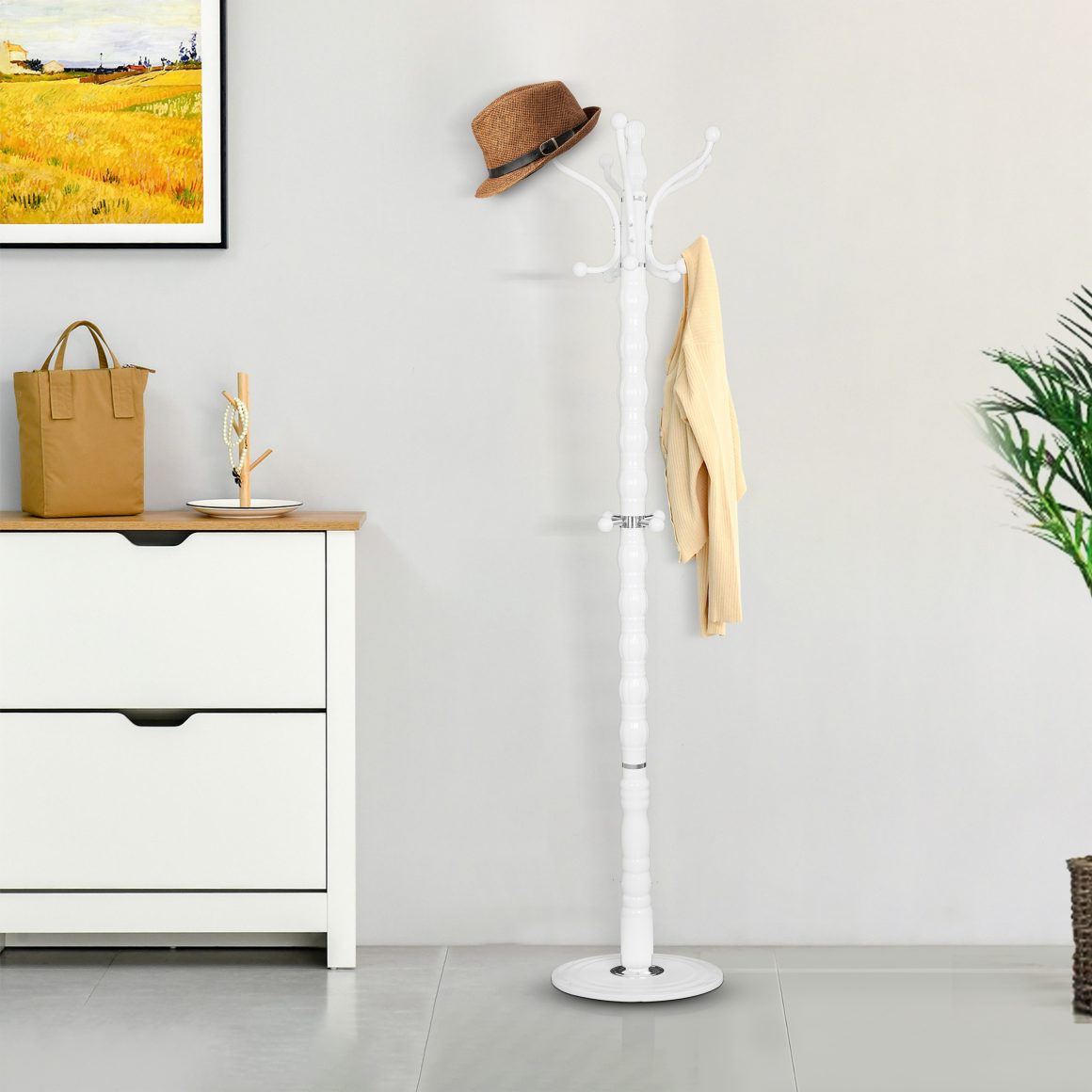 espace incluant portemanteau blanc avec chapeau et vêtement, meuble blanc, tableau et plante.
