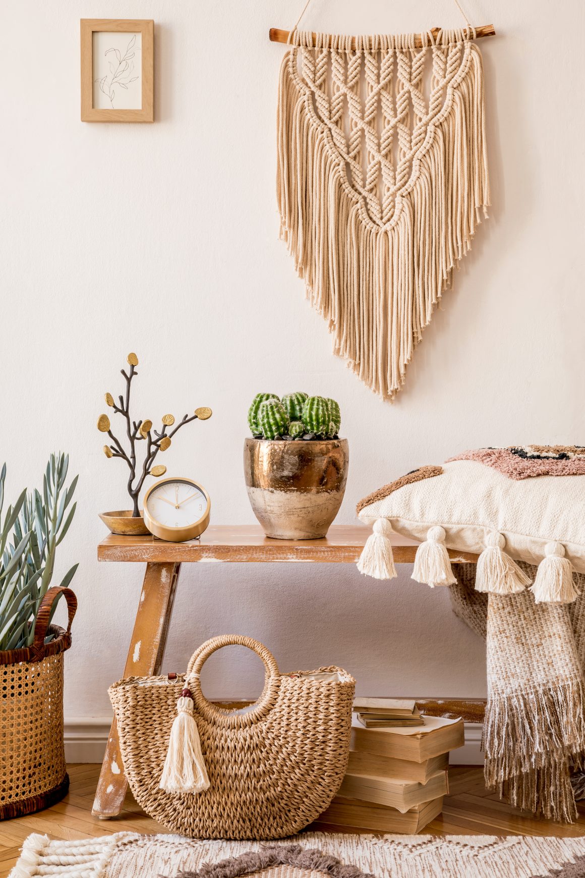 Intérieur bohème avec macramé mural, cactus en pot, panier tressé, coussin à pompons et plante.