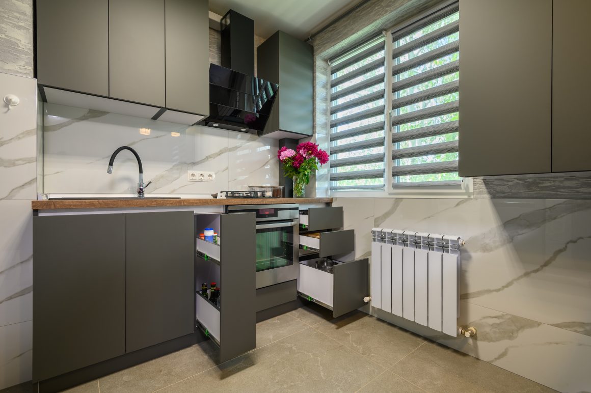 Cuisine compacte avec tiroirs intégrés, rangements verticaux, fenêtre, plan de travail surdimensionné et placards jusqu'au plafond.