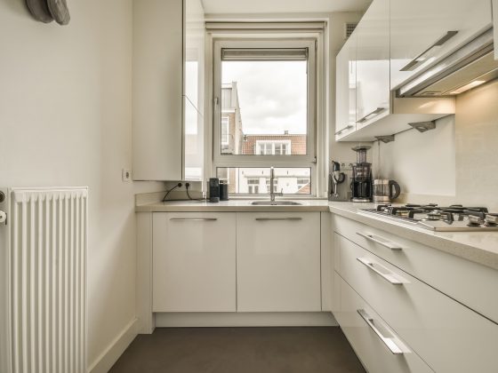 Aménagement petite cuisine 4m2 avec armoires, un plan de travail, une plaque de cuisson intégrée avec un évier sous fenêtre.