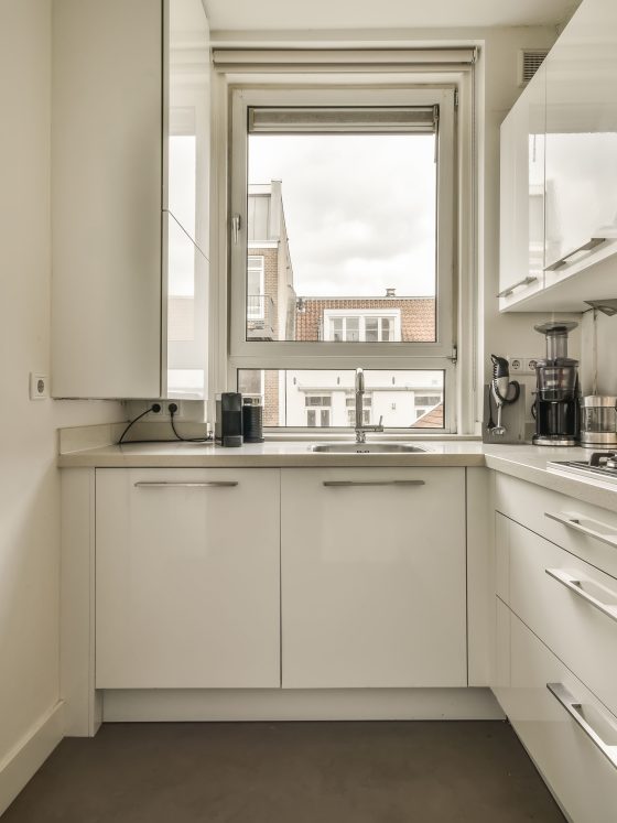 Aménagement petite cuisine 4m2 avec armoires, un plan de travail, une plaque de cuisson intégrée avec un évier sous fenêtre.