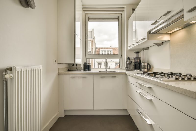 Aménagement petite cuisine 4m2 avec armoires, un plan de travail, une plaque de cuisson intégrée avec un évier sous fenêtre.