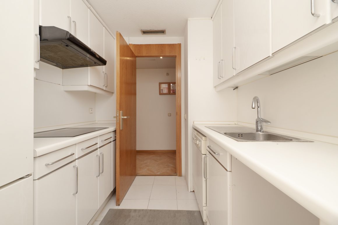Aménager petite cuisine 4m2 avec armoires hautes, hotte aspirante discrète, évier et un carrelage blanc au sol.
