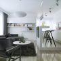 Cuisine ouverte sur salon 25m2 avec mobilier blanc brillant, canapé, table basse, tapis et étagères murales.