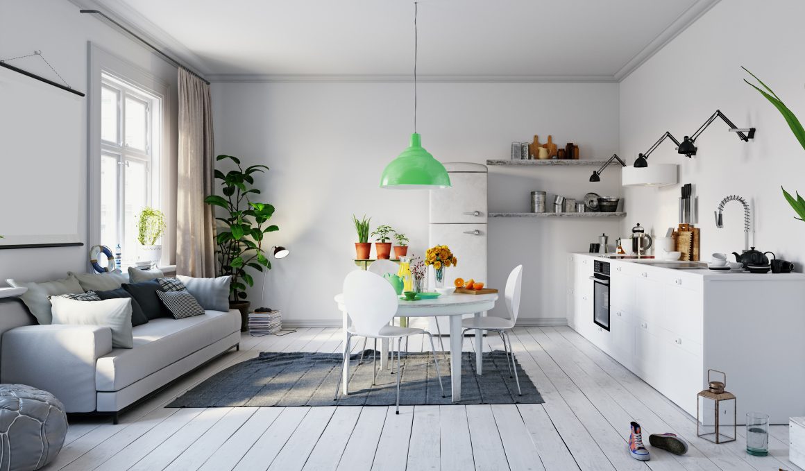 Cuisine et salon lumineux avec mobilier blanc, table ronde avec chaises, plantes et lampe verte suspendue.