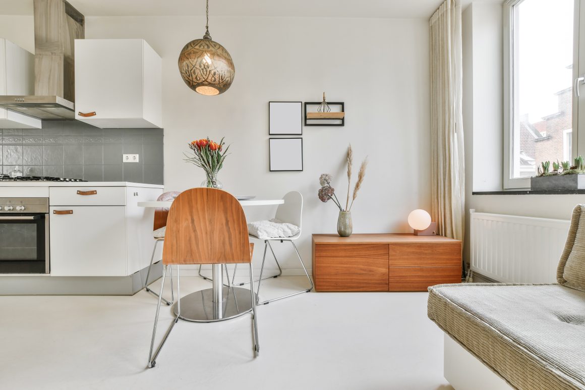 Un salon lumineux avec meuble en bois, lumière douce, plantes et cuisine ouverte.