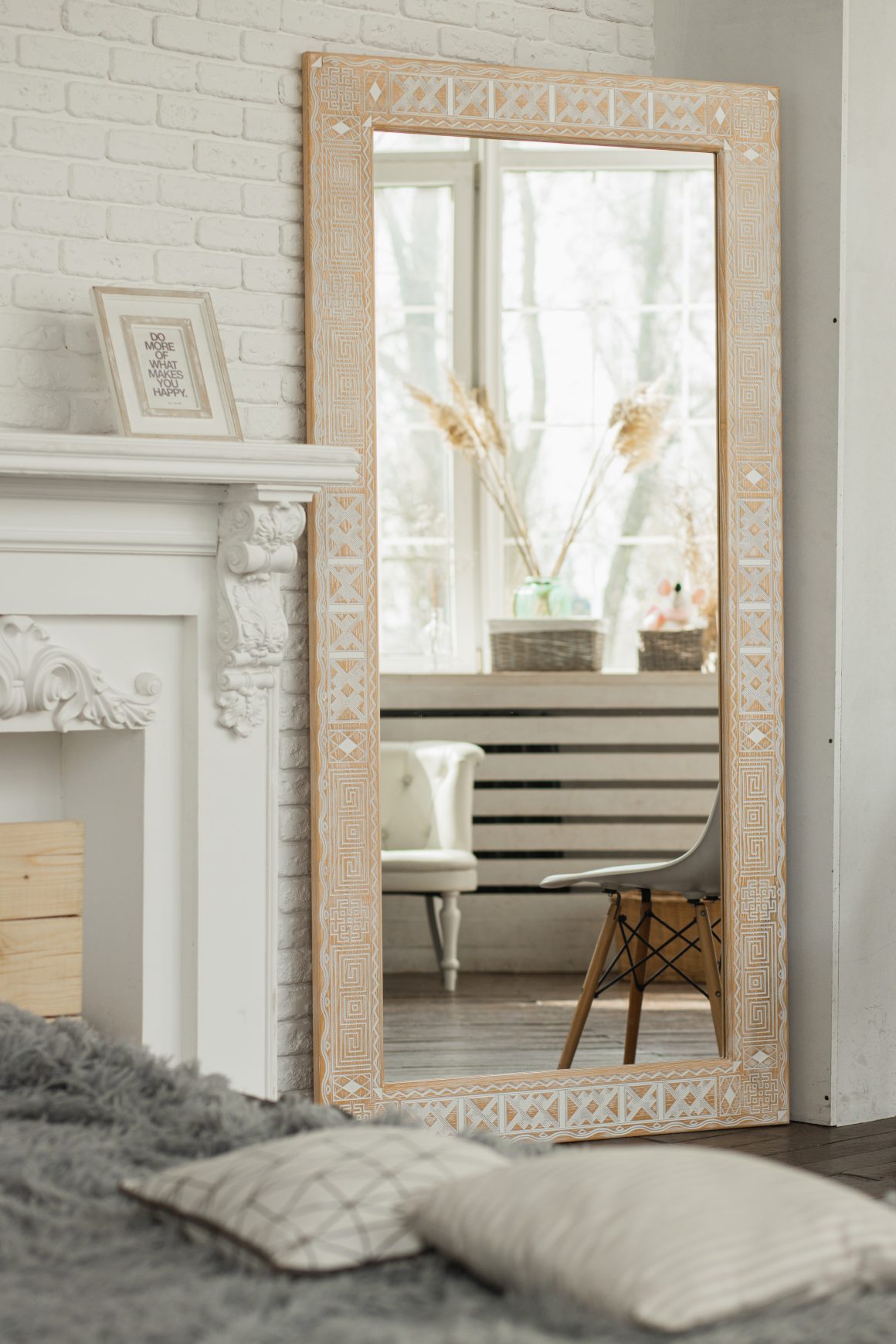 Miroir encadré en bois sculpté, tapis, coussins et chaise dans un intérieur minimaliste
