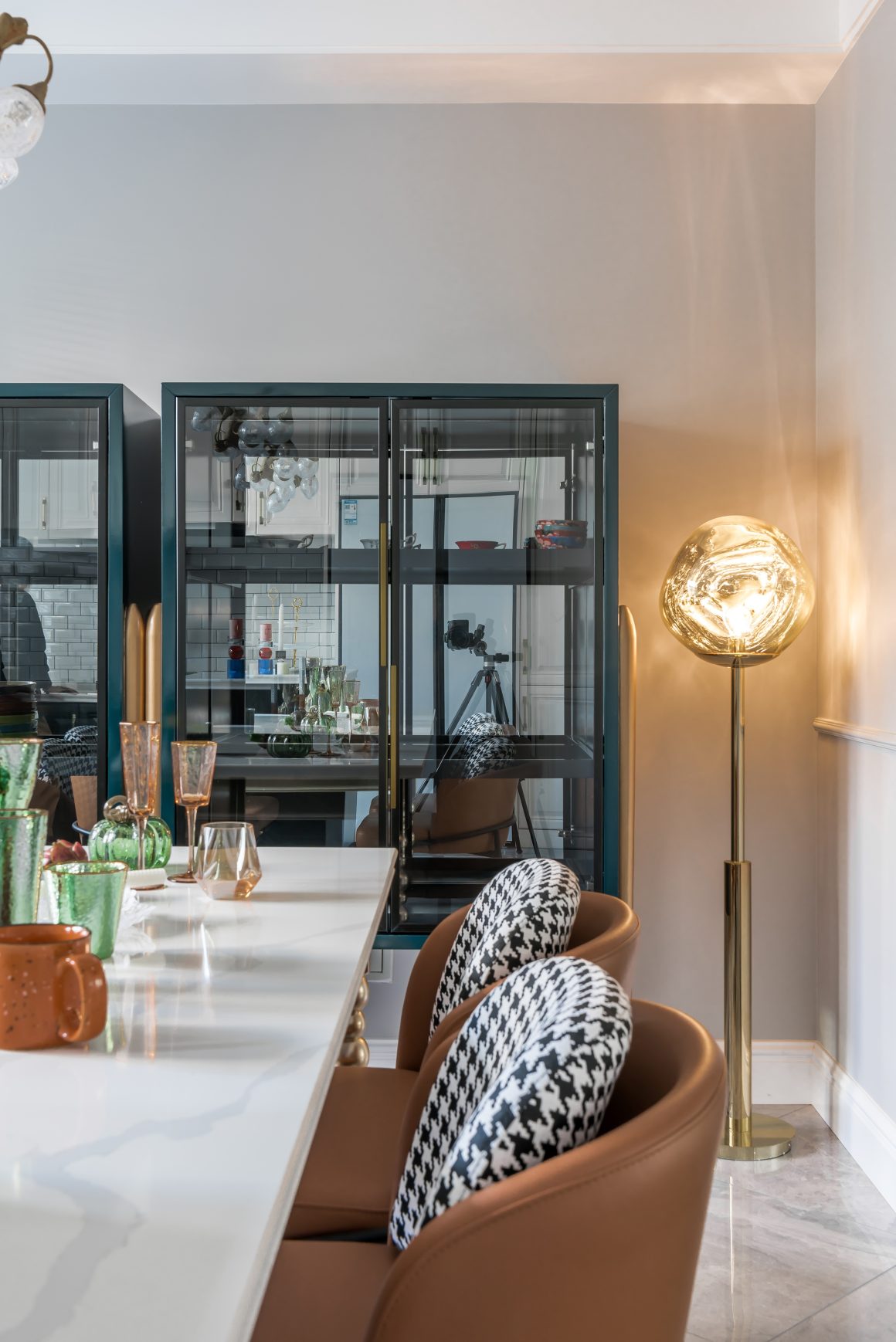 Salle à manger élégante, lampadaire moderne, mobilier en cuir et armoire vitrine.