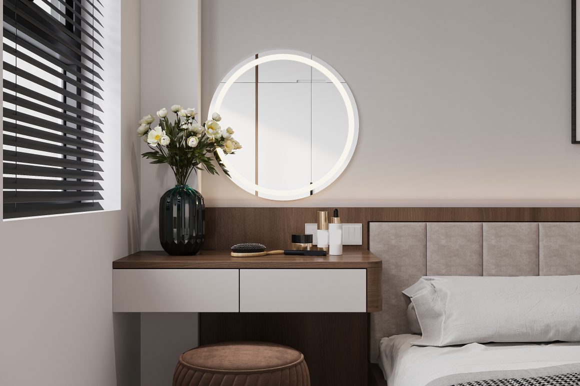 Un coin chambre moderne avec coiffeuse en bois, miroir rond lumineux, tabouret marron, fleurs blanches, et coussin gris clair.