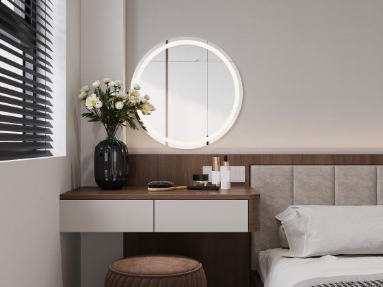 Un coin chambre moderne avec coiffeuse en bois, miroir rond lumineux, tabouret marron, fleurs blanches, et coussin gris clair.