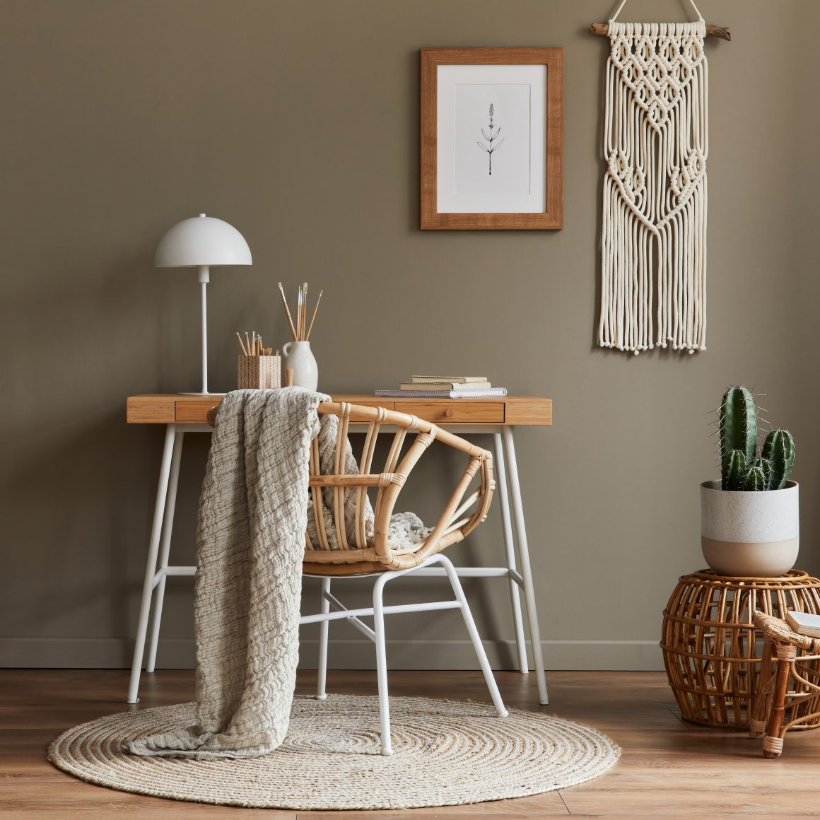 Coin bureau avec chaise en rotin, décoration murale en macramé beige et plante cactus.