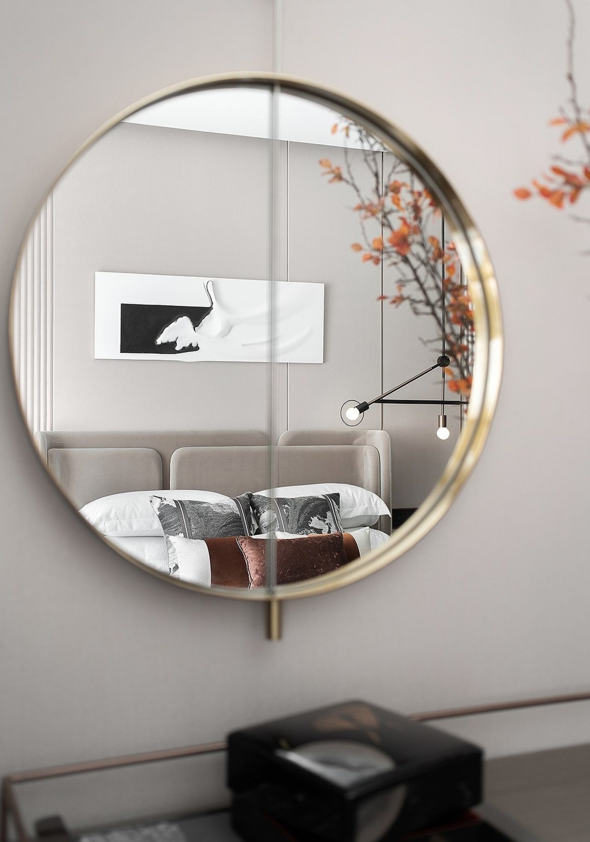 Chambre avec déco minimaliste, lit beige, tableau blanc noir et miroir rond.
