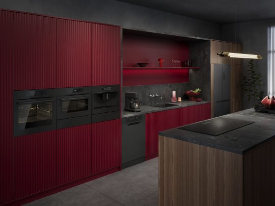 modèle de cuisine moderne aux tons bordeaux et gris avec appareils encastrés noirs, plan de travail en pierre et îlot en bois.